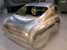 a car body sitting on top of a white floor next to a black and silver object