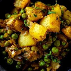 a black bowl filled with potatoes and peas