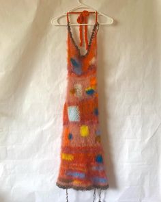 a knitted dress hanging on a white hanger with an orange and blue design