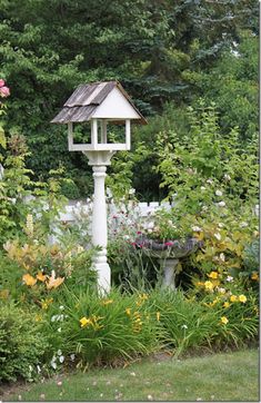 a white birdhouse sitting in the middle of a garden