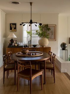 a dining room table with chairs and a potted plant in the corner next to it