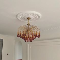 a chandelier hanging from the ceiling in a room with white walls and doors