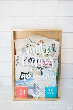 a wooden box filled with lots of different types of paper and magnets on top of a white brick wall