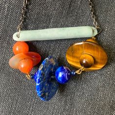 For your consideration: Handmade Modern Bar Necklace with Lapis, Carnelian, Tiger Eye bead and donut links on an antique jade bar.  It is hard to describe this necklace: 3 Saturn flying saucer type links consisting of 2 round and one donut shaped bead hang from an antique jade bar. The links are carnelian, lapis lazuli and tiger eye.  The necklace has an approximate 15" drop on a gunmetal color metal chain.  It has a modern yet primitive and spiritual look.  Please see pictures and dm me with questions. Antique Jade, Donut Shape, Flying Saucer, Tiger Eye Beads, Modern Bar, Handmade Modern, Bar Necklace, Metal Chain, Tiger Eye