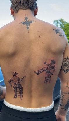 a man with tattoos on his back standing next to a car