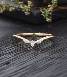 a gold ring with three pear shaped diamonds on it, sitting on a wooden table