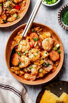 two bowls filled with shrimp and vegetables next to a bowl of bread on a table