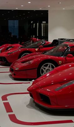 a row of red sports cars sitting on top of a white floor