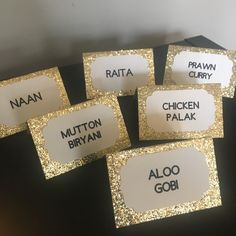 five place cards with names on them sitting on a table in front of a black box