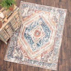 an area rug on the floor next to a wooden table with a potted plant