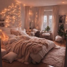 a bedroom with lights on the wall and a bed covered in fluffy blankets, pillows and blankets