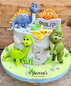 a birthday cake decorated with dinosaurs and the number three