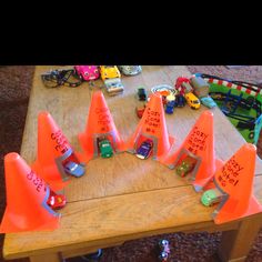 a wooden table topped with lots of traffic cones and toy cars sitting on top of it