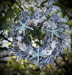 a wreath with starfishs and seashells hanging from it's sides