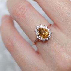 a woman's hand with a yellow and white diamond ring on top of it