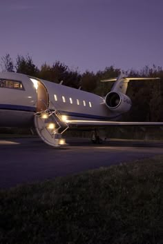 an airplane with its door open on the runway at night, lit up by lights