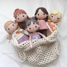 a group of knitted dolls sitting in a crochet basket on top of a white sheet