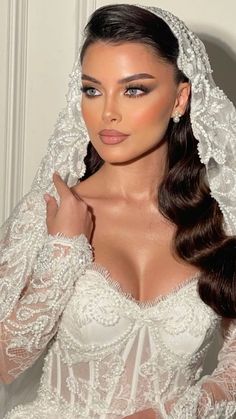 a woman in a wedding dress with a veil on her head and long brown hair