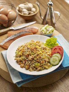 a white plate topped with rice and veggies on top of a wooden table