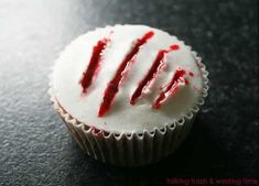 a cupcake with white frosting and red sprinkles sitting on a table