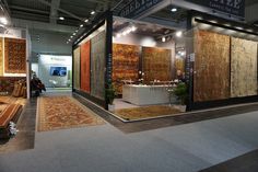 an exhibit room with rugs on display and people sitting in the background looking at them