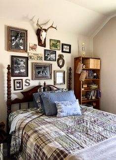 a bed room with a neatly made bed and lots of pictures on the wall above it