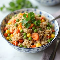 a bowl filled with rice and vegetables on top of a table next to a fork