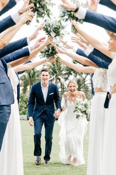 a bride and groom walking through a group of people holding their hands in the air