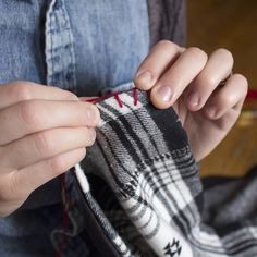 a woman is stitching something on her jeans with a red string and thread in her pocket