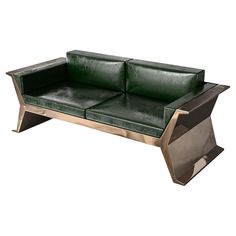 a green leather couch sitting on top of a metal frame table with an open end