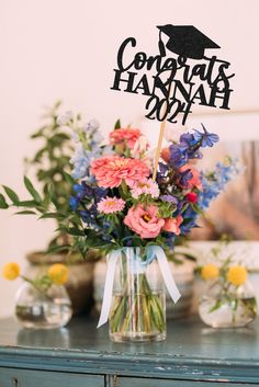 a vase filled with flowers on top of a wooden table next to a sign that says congratulations hannah 2009