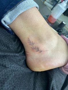 a woman's foot with a small leaf tattoo on it