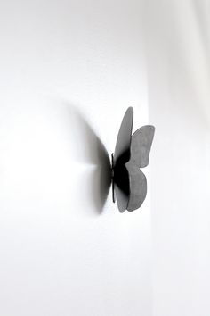 a metal butterfly mounted to the side of a white wall