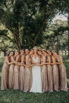 a group of women standing next to each other in front of a lush green field