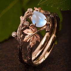 a close up of a ring with an opal in the center and leaves on it