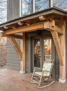 a rocking chair sitting on top of a wooden porch next to a building with windows