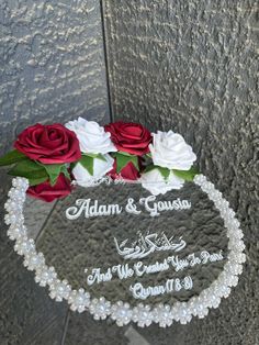 two roses are placed in the middle of a glass plaque that reads, adam and gusa