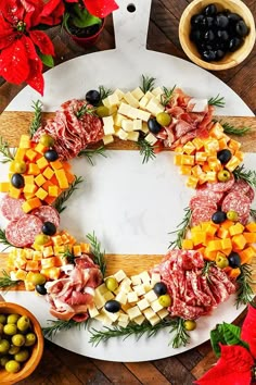 a platter filled with meats, cheese and olives on top of a wooden table