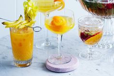 three different types of cocktails on a marble counter top with fruit and flowers in the background