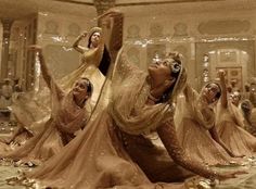 several women dressed in gold and white dance on the floor with their arms spread out