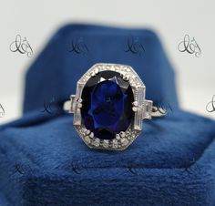 a ring with a blue stone surrounded by white diamonds on a blue velvet cushioned surface