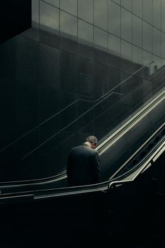 a man is riding down an escalator on his cell phone in the city