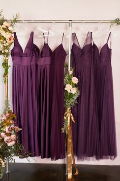 three bridesmaids in purple dresses hanging on a rack