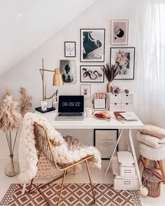 a white desk topped with a laptop computer next to a chair and pictures on the wall