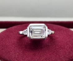 East West Emerald Cut Ring, Moissanite Emerald Cut Engagement Ring, Bezel Set Emerald Ring, Unique Horizontal Ring, Promise Rings For Women ▶ Product Details ◀ ◼ Metal: 10K/14K Solid Yellow/White/Rose Gold & 925 Sterling Silver  ◼ Stone Details : ▪ Stone Type :               Simulated Diamond (Cubic Zirconia) ▪ Diamond Color :        D/White  ▪ Diamond Clarity :      VVS1 ▪ Diamond Shape :      Emerald Cut & Round Cut ▪ Center Stone Size:    8x6 mm                  ▪ Center Stone Weight : 1.75 Ct ◼ Moissanite Stone Details : ▪ Stone Type :               Moissanite ▪ Diamond Color :        Near Colorless ▪ Diamond Clarity :      VVS1                      ▪ Diamond Shape :      Emerald Cut & Round Cut                   ▪ Center Stone Size:    8x6 mm                  ▪ Center Stone Weight : 1 Emerald Cut Rings, Emerald Engagement Ring Cut, Colorless Diamond, Emerald Cut, White Rose Gold, Emerald Ring, Moissanite Diamonds, Diamond Clarity, Bezel Setting