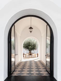 an archway leading to a large tree in the middle of a room with black and white checkered flooring