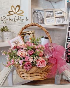 a basket filled with pink flowers sitting on top of a glass table next to pictures