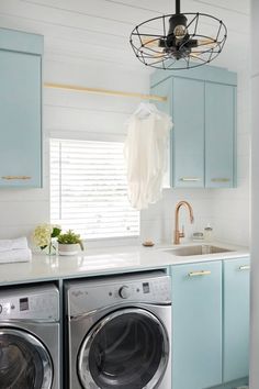 a washer and dryer in a small room with blue cabinets, white walls and flooring