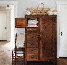 a wooden cabinet sitting in the corner of a room with a basket on top of it