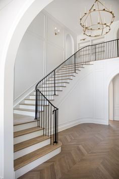 a white staircase with black railing and chandelier